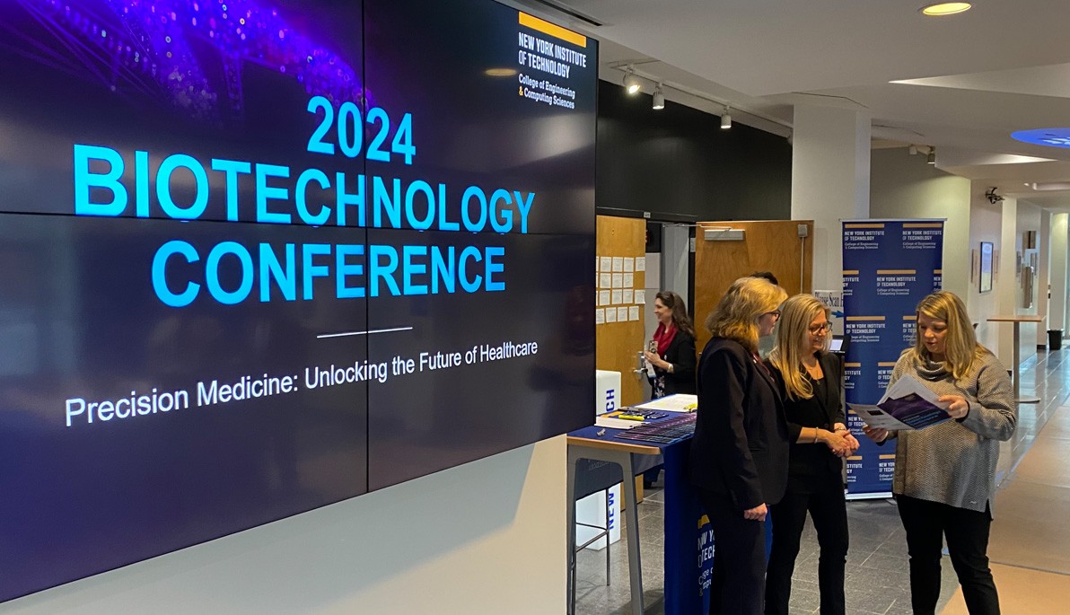 Three people standing next to a digital sign that reads 2024 Biotechnology Conference