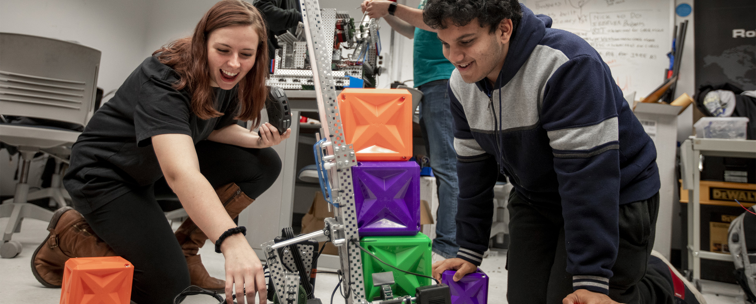 Mechanical engineering students working on project with colorful boxes