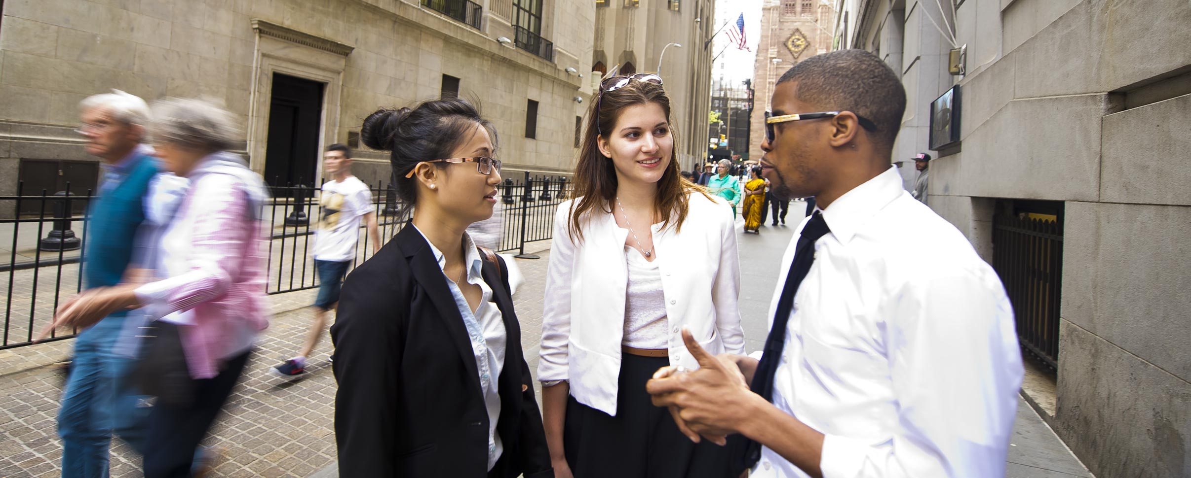 Three business students talking on city street