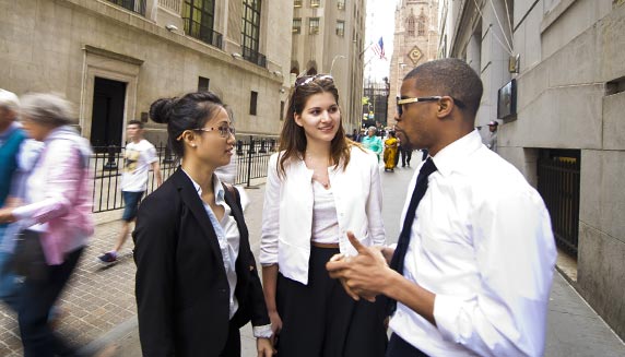 Three business students talking on city street