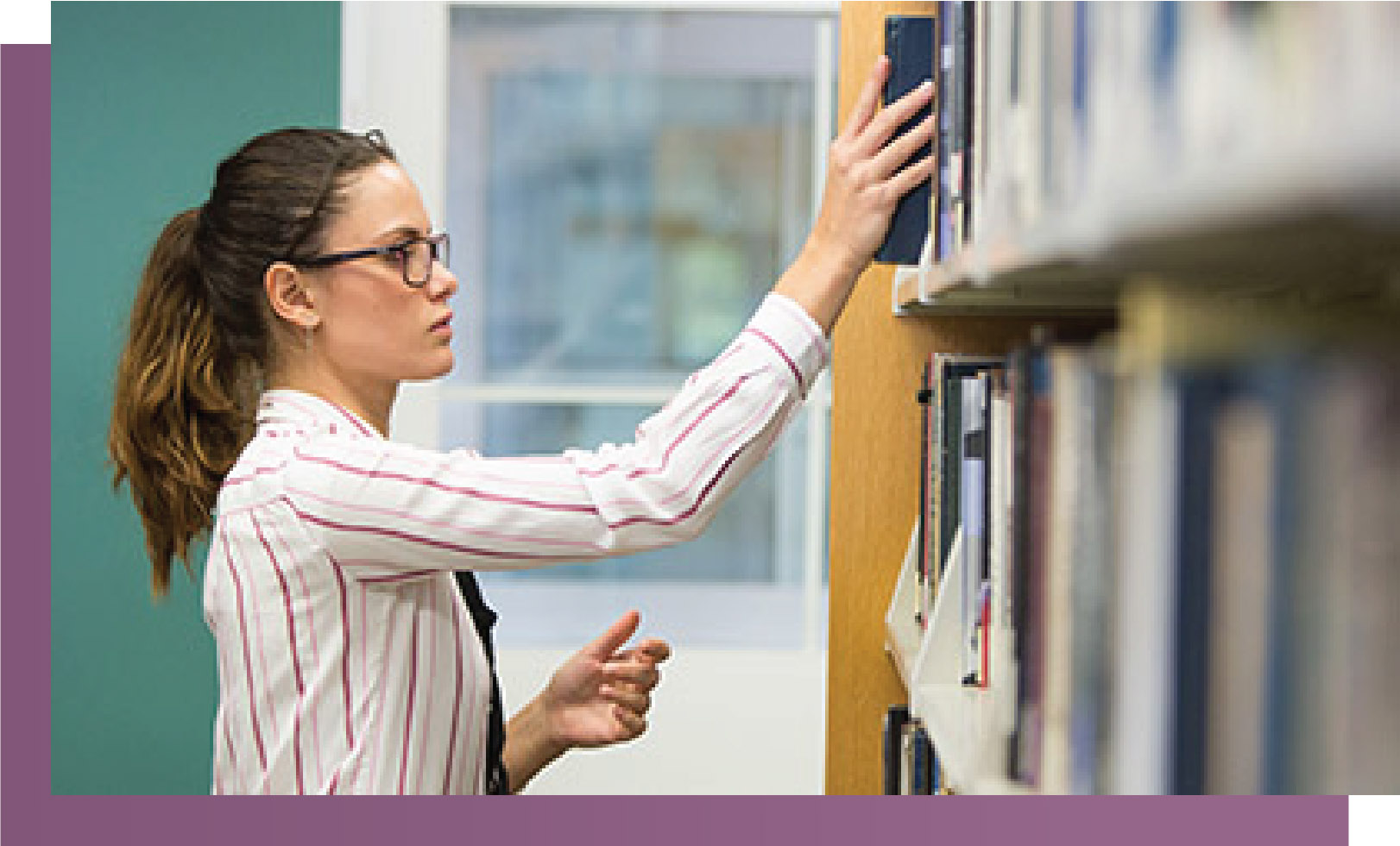 Young woman pulling book from shelf at library