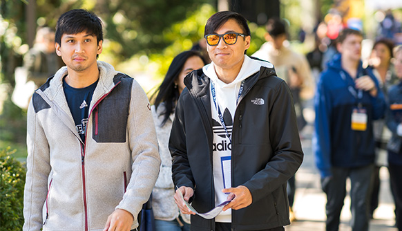 Two male students in front of crowd on campus