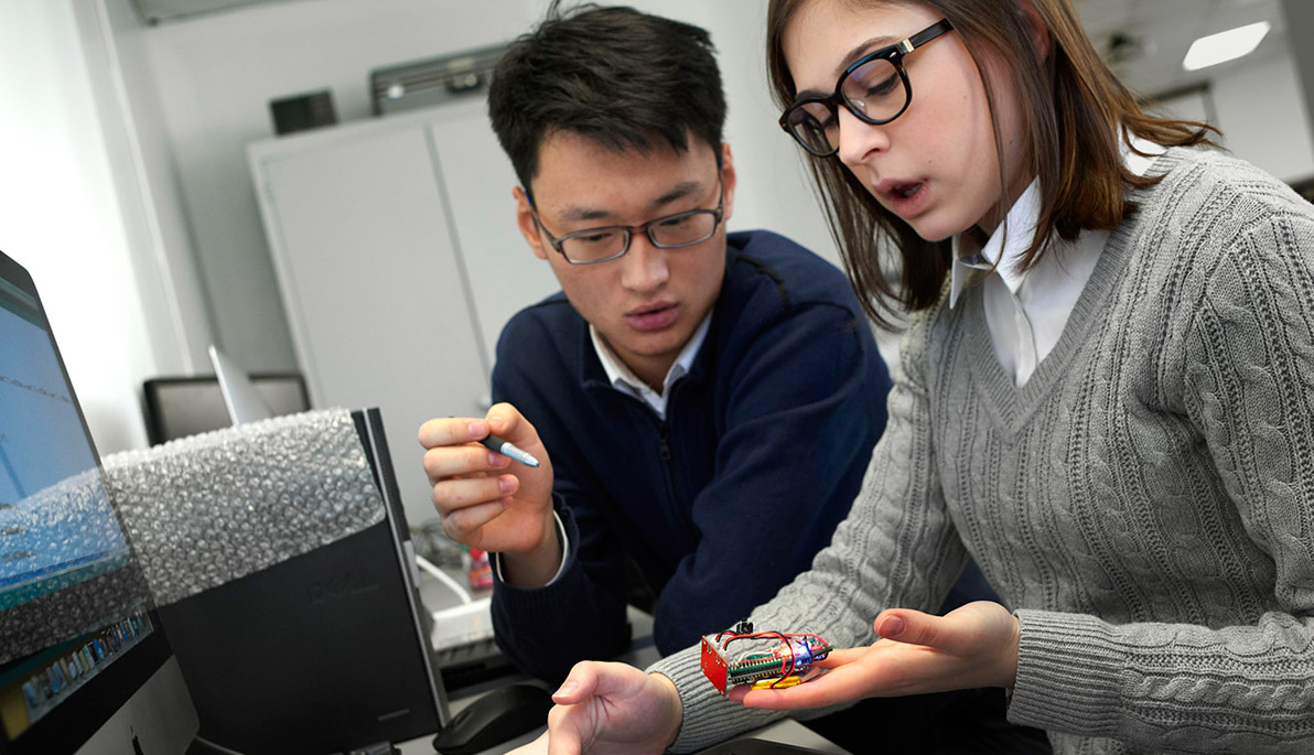 Two NYIT students looking at computer component