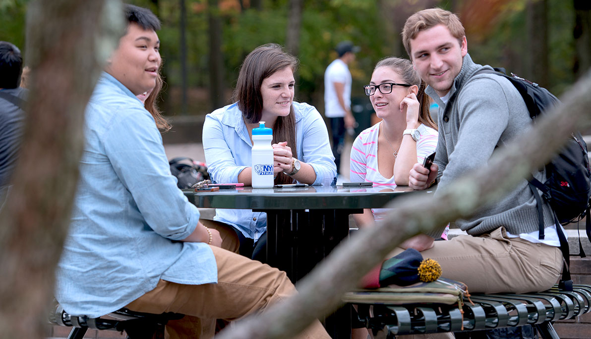 NYIT students sitting at a table on campus.