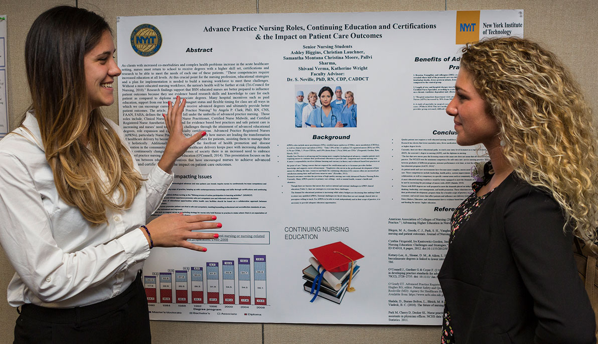 Two female NYIT students looking at a poster presentation.