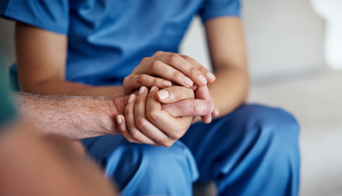 Image of a healthcare professional holding a patient’s hand.