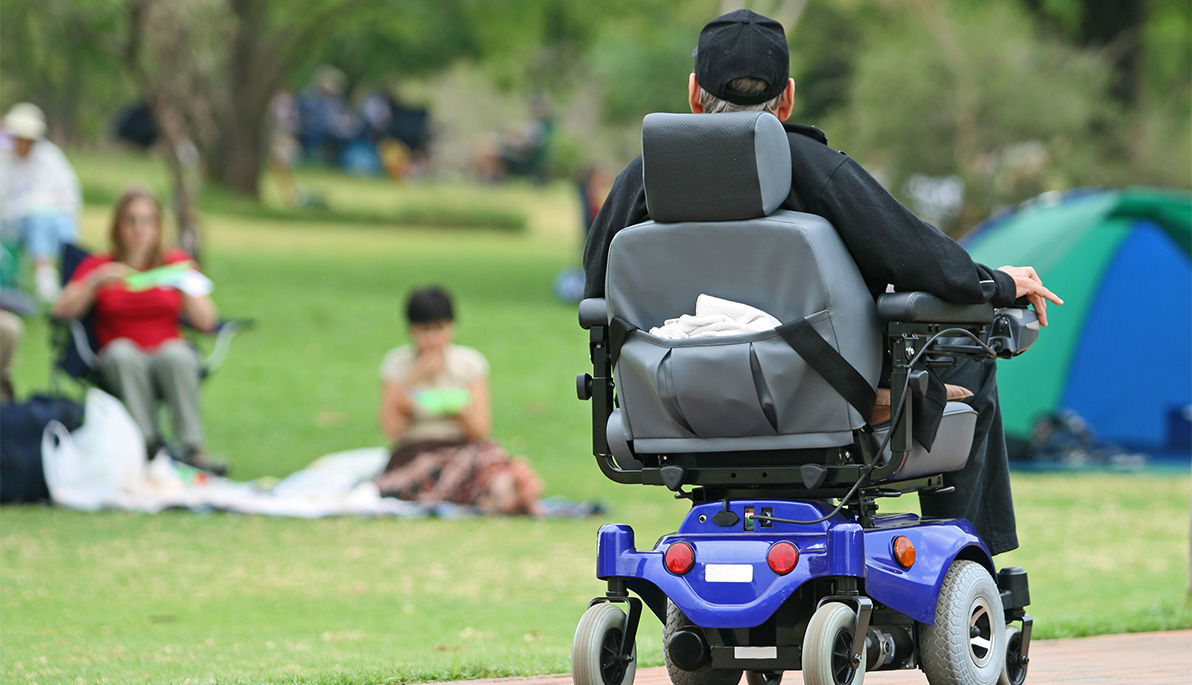 A man in a motorized wheelchair in a park