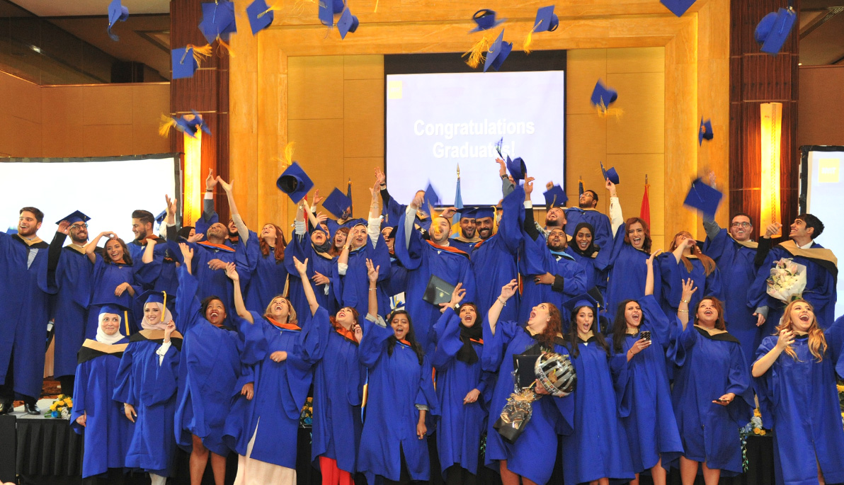 NYIT-Abu Dhabi graduates throwing hats in the air.