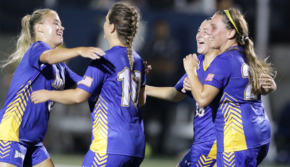 NYIT women’s soccer players celebrate a goal.
