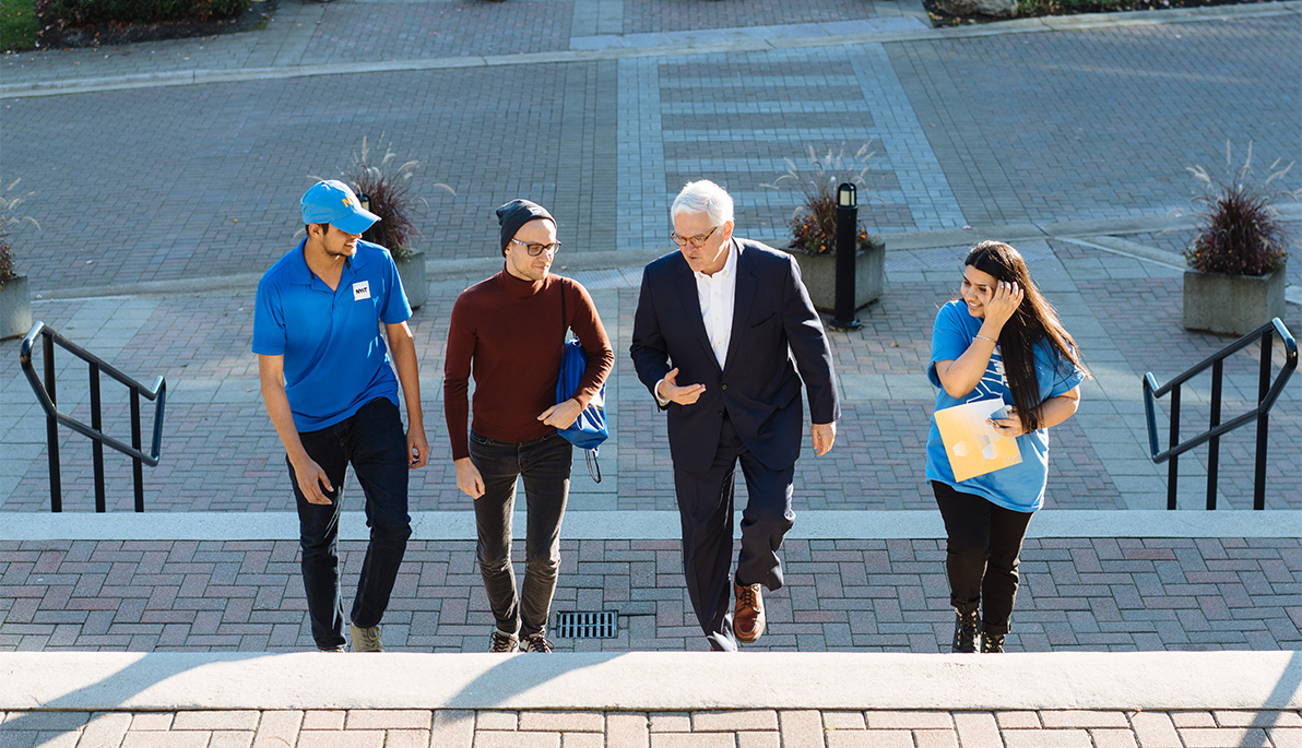 NYIT President Hank Foley walking with students.