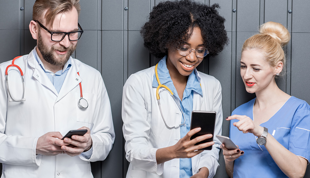 Three healthcare professionals looking at their mobile phones.