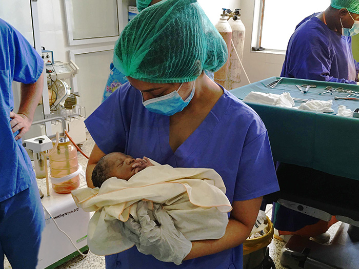Medical student Anita Thomas holds a newborn at Hawa Memorial Saviour Hospital