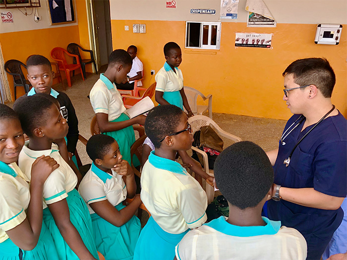 Medical student Tyler Nghiem demonstrates how to take vitals to school children