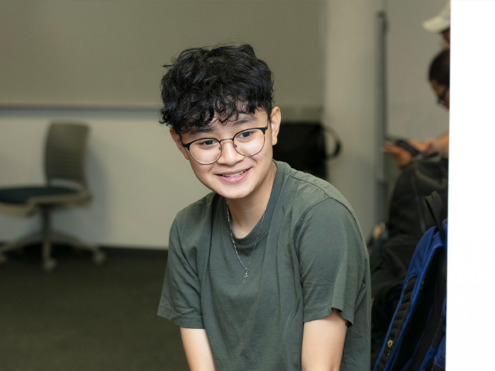 Close-up of student with short wavey hair, glasses and green shirt