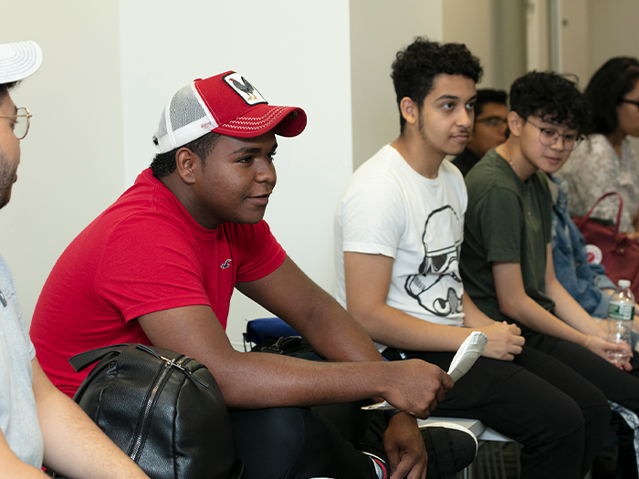 Student in red shirt and red baseball cap sitting in group of students