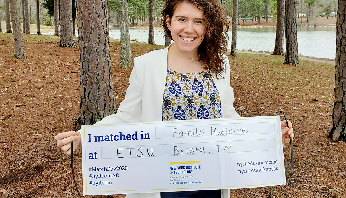 Medical student Kayla Arthur holding a sign showing her match.