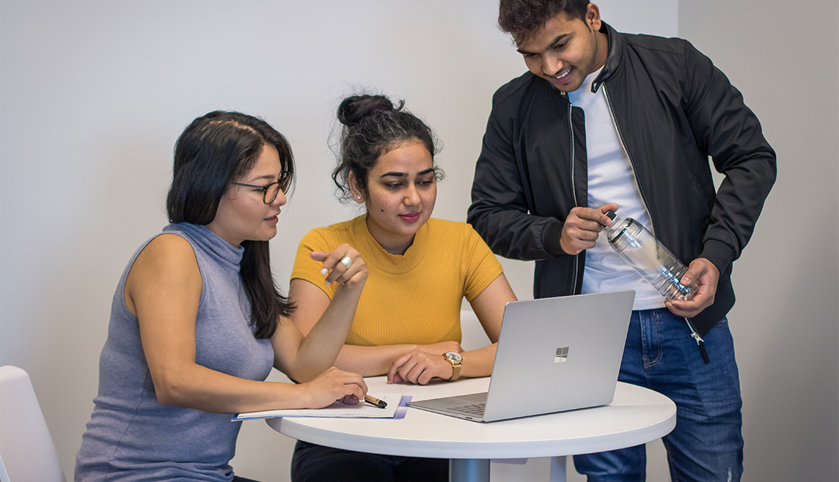 Three international students looking at a laptop computer