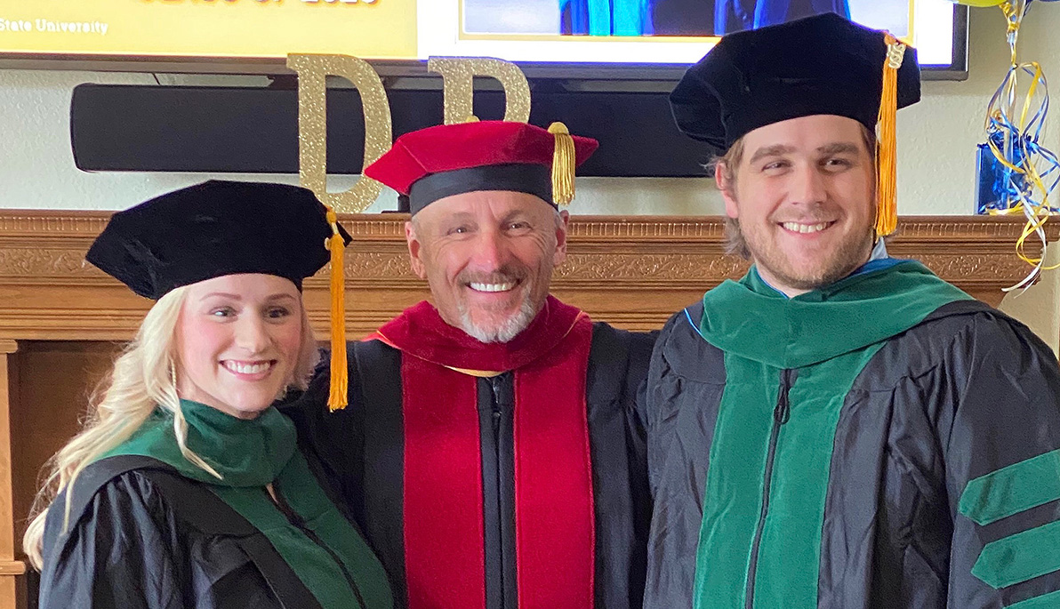 A proud family of doctors: a father, his daughter, and son-in-law, in academic regalia.