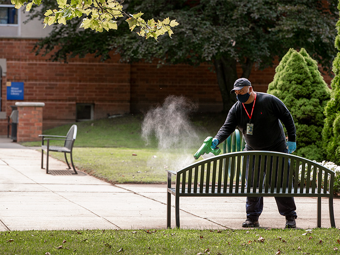 Facilities worker disinfecting bench