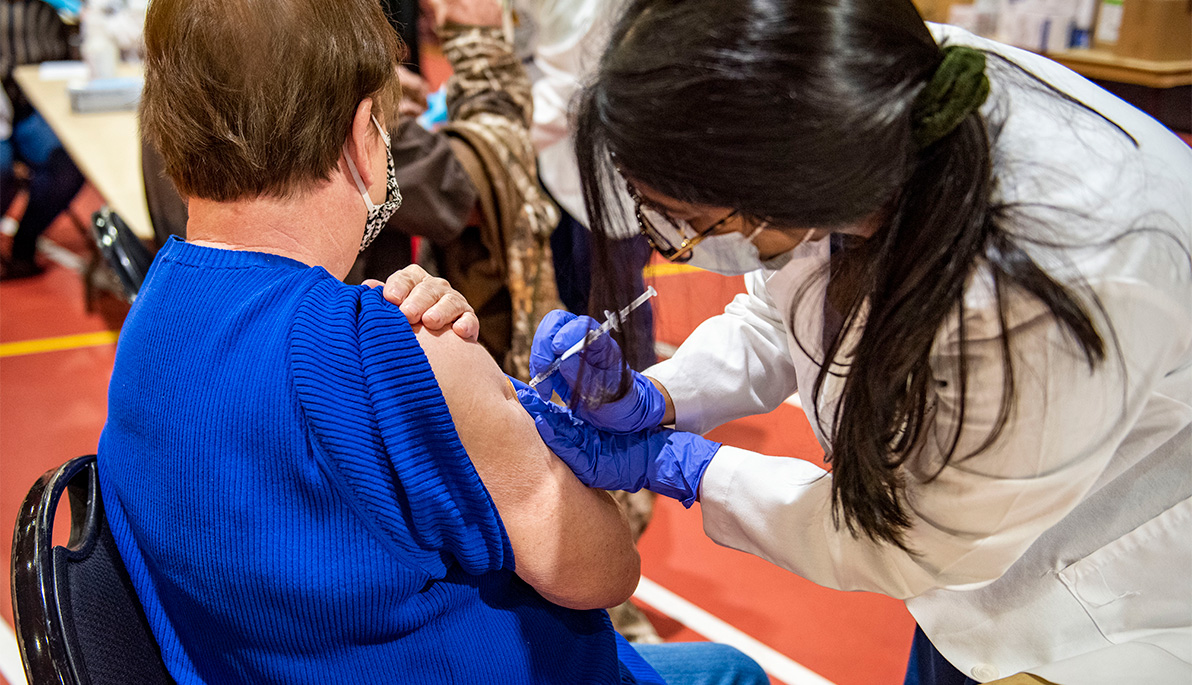 NYITCOM student administering a vaccine.