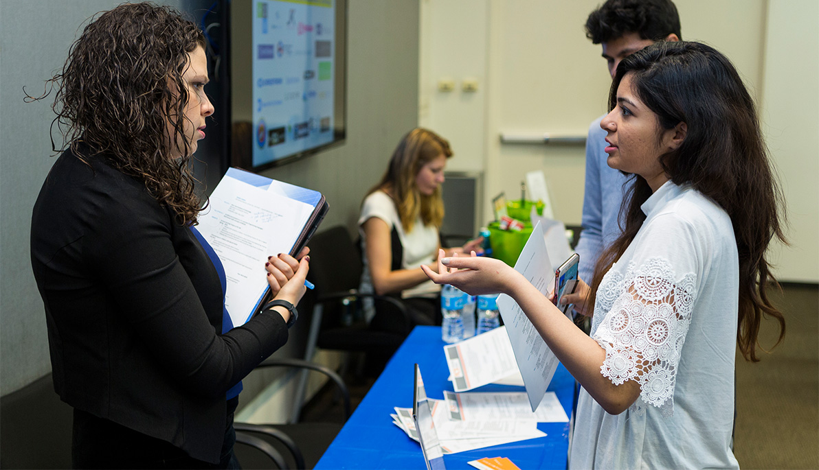 Student speaking with a prospective employer at a New York Tech career fair