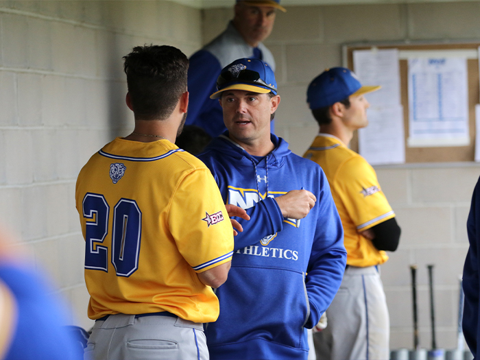 Head Coach Frank Catalanotto speaks with catcher Matt Malone in the home dugout at Angelo Lorenzo Memorial Baseball Field while other players watch game