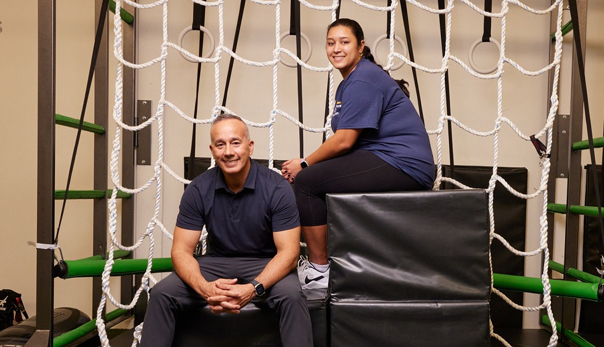 Two people sitting on gym equipment
