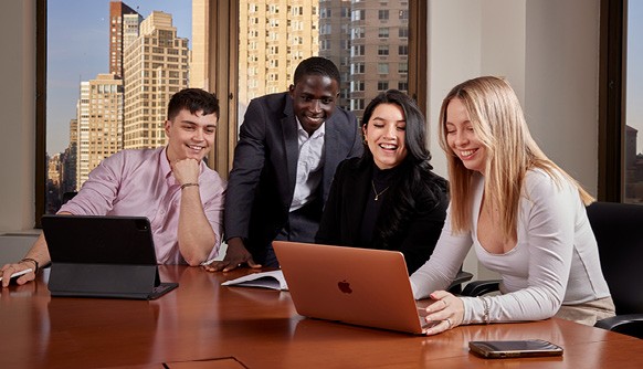 New York Tech students sitting at a conference table looking at a laptop