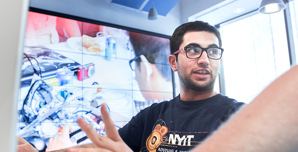 NYIT student in front of HD video wall
