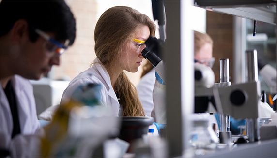 Student in lab wearing goggles and a labcoat