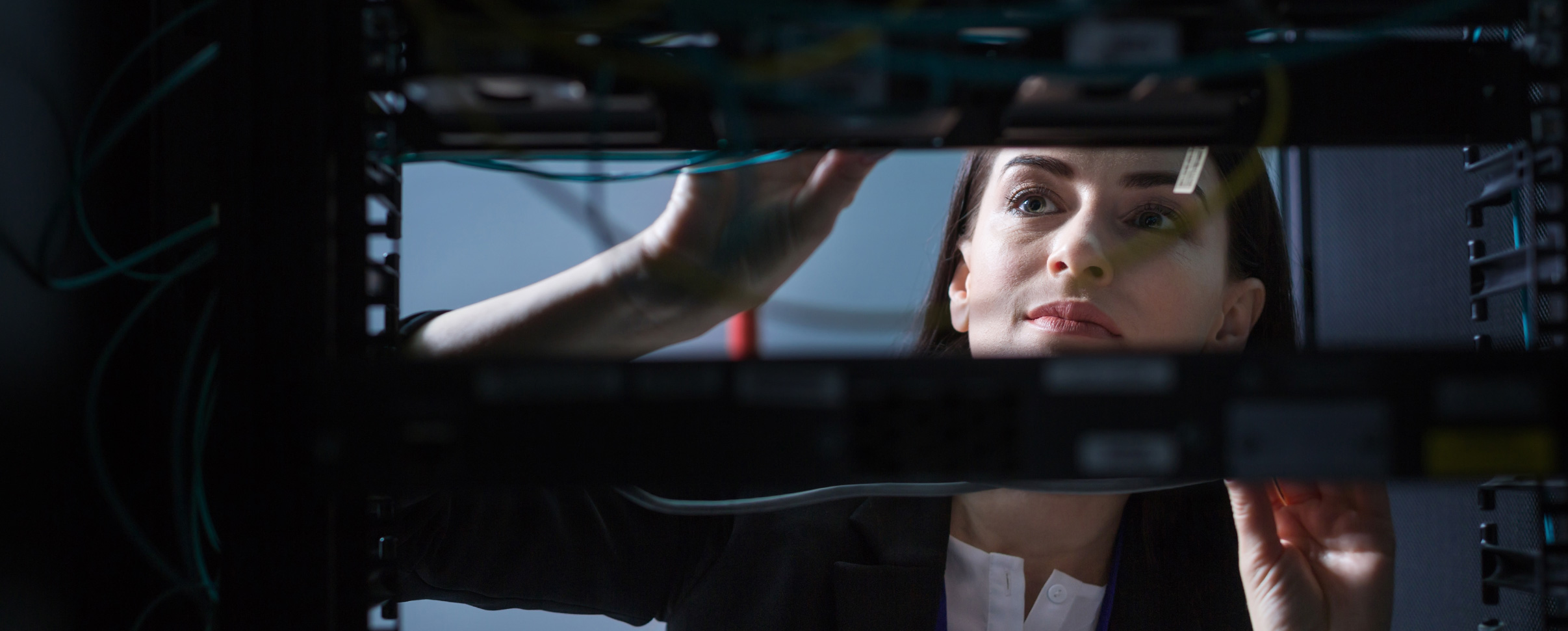 View of young woman through electronic equipment as she checks network wires