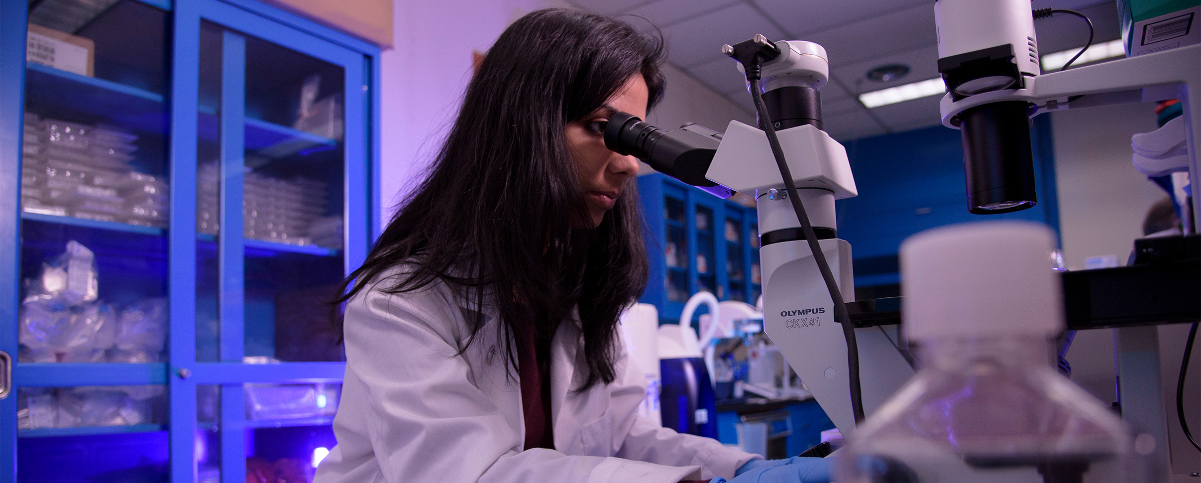 Female scientist looking through a microscope. 