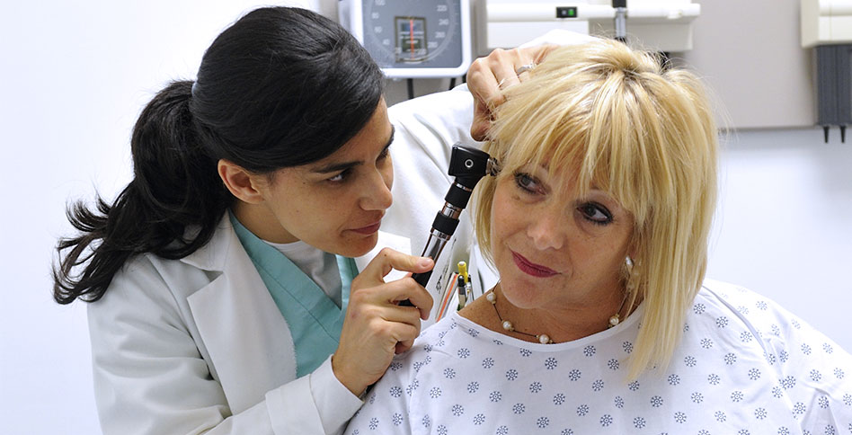 Doctor checking patient's ear with otoscope.