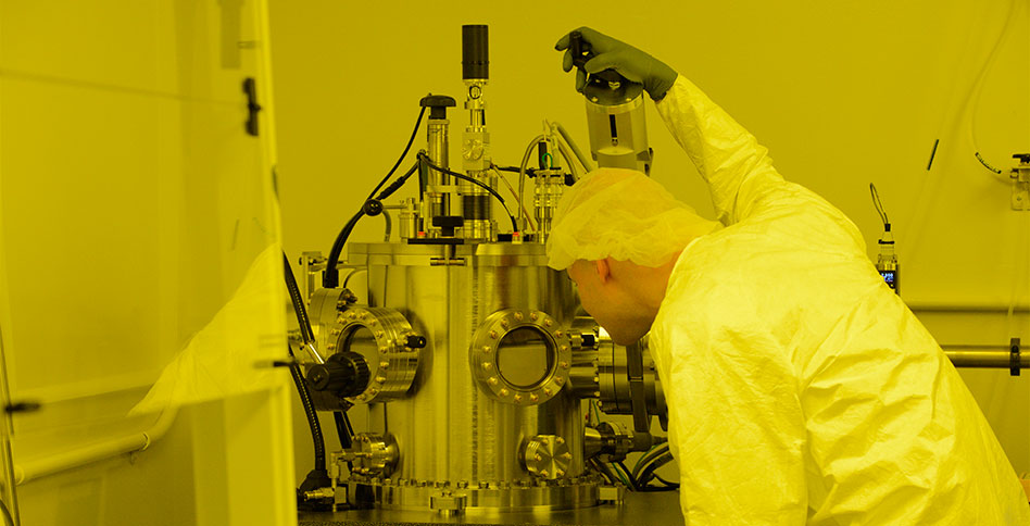 Researcher in protective gear working in nanofabrication facility