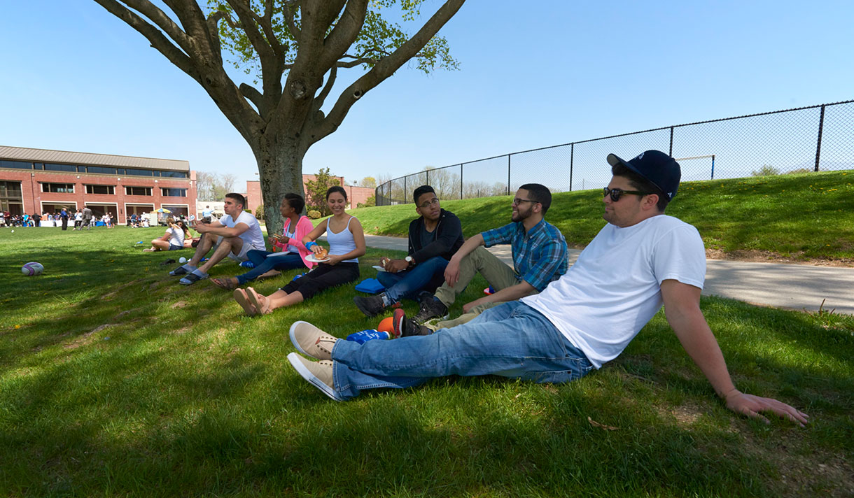 Students sitting on lawn and enjoying burgers