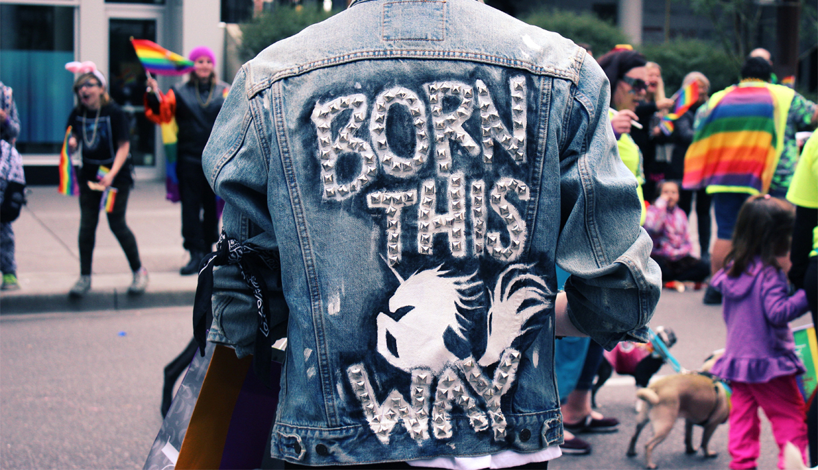 Person wearing denim jacket that says "Born This Way" on the back