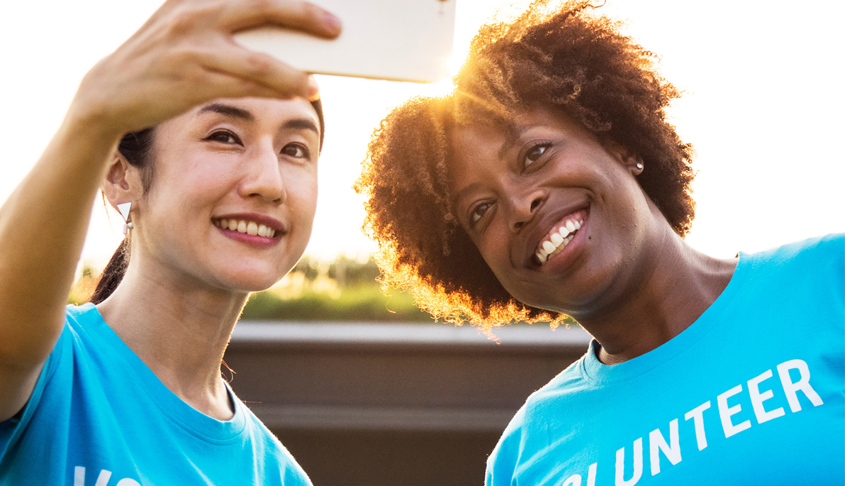Two women wearing "volunteer" shirts taking a selfie