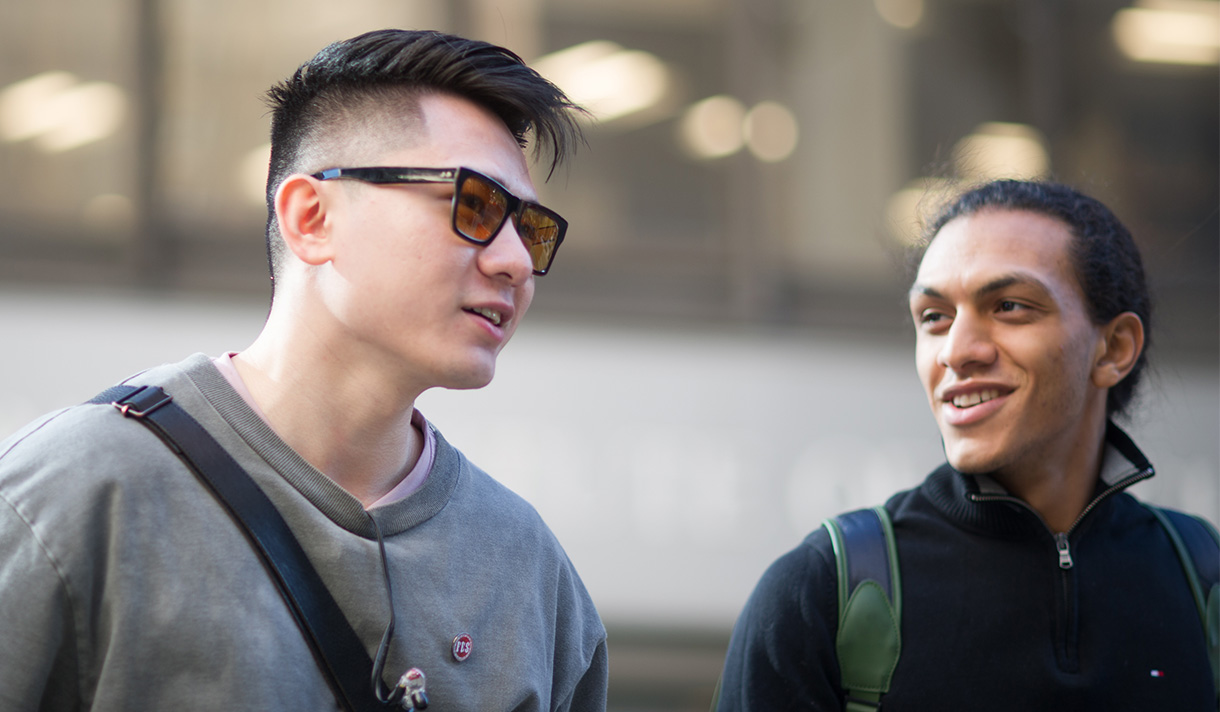 Close-up of two students walking and talking outside on campus.