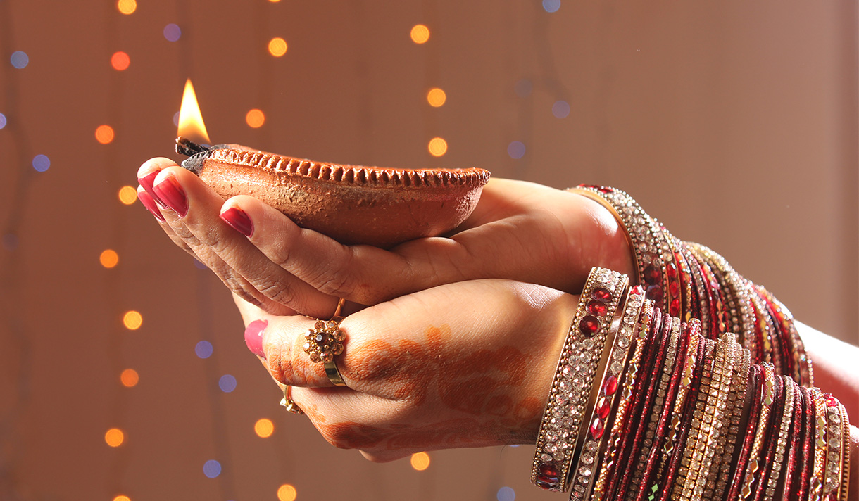 Clasped hands adorned with fine jewelry holding a ceremonial flame