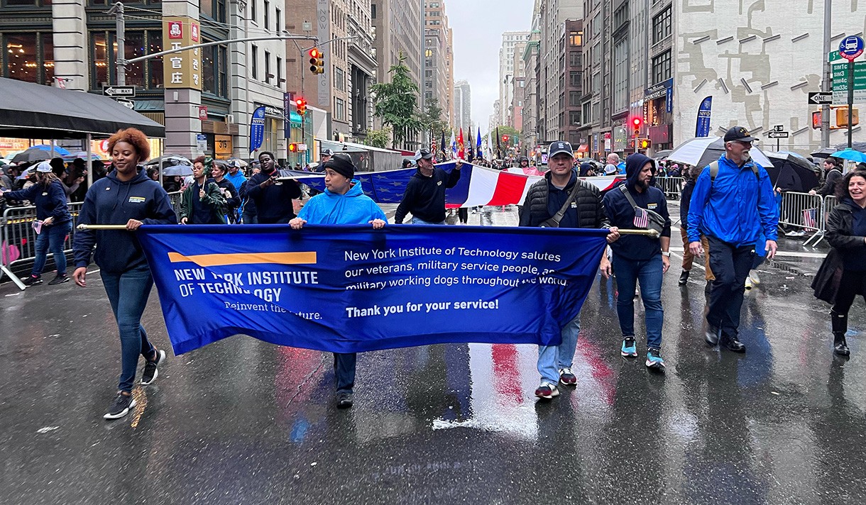 New York Tech students marching in the Veterans Day Parade with a banner