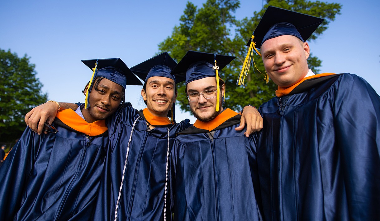 Four graduates in cap and gown