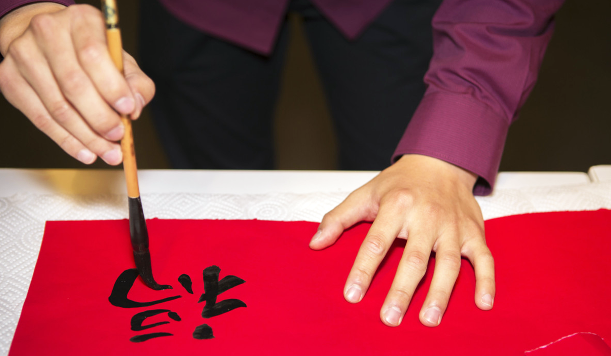 Someone writing Chinese calligraphy on red cloth