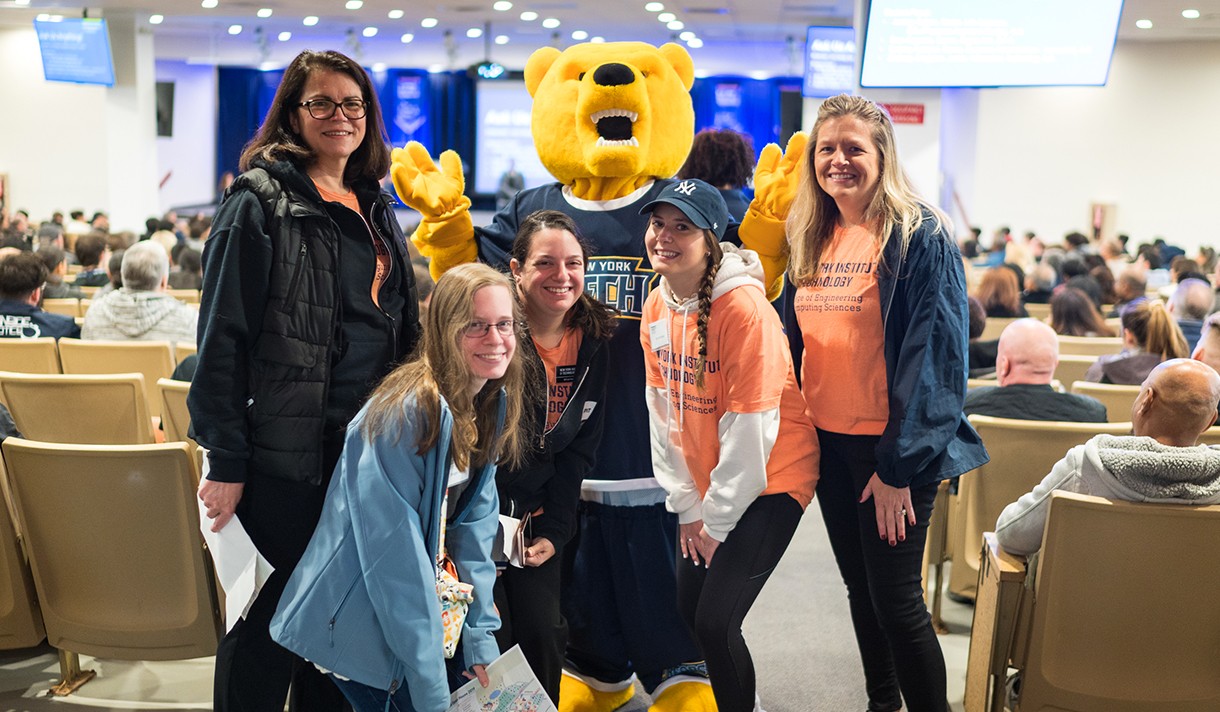 Students posing around New York Tech "Roary" the Bear mascot