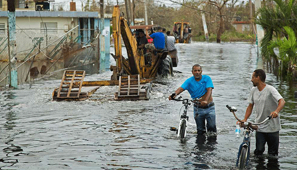 people walking bicycles through flooded streets in Puerto Rico