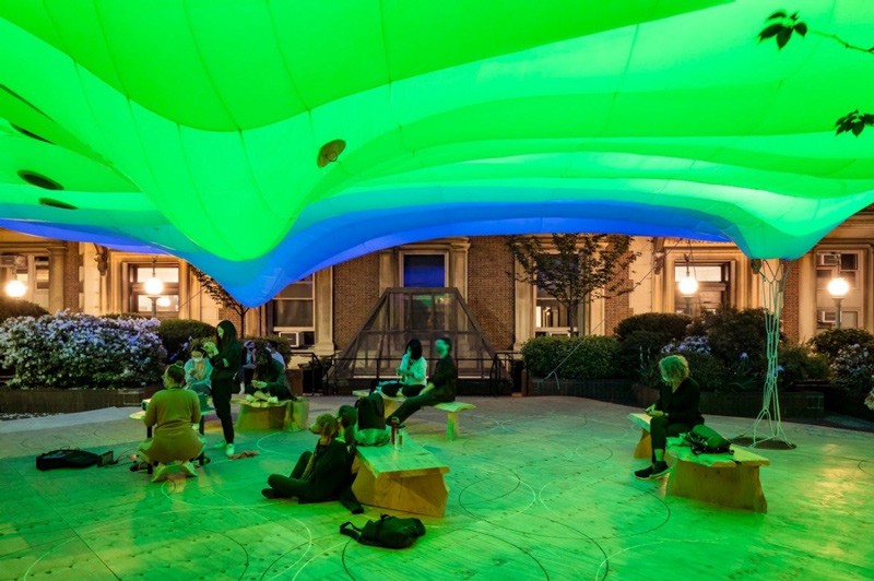 people sitting under an illuminated tent with various colored lights