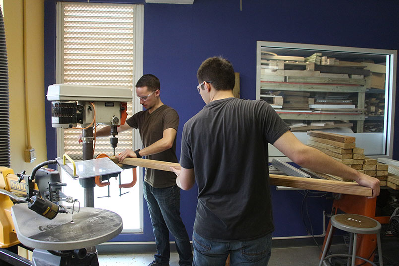 NYIT architecture students Kevin Kaweicki and Chris Cetola drill holes into a wooden slat.