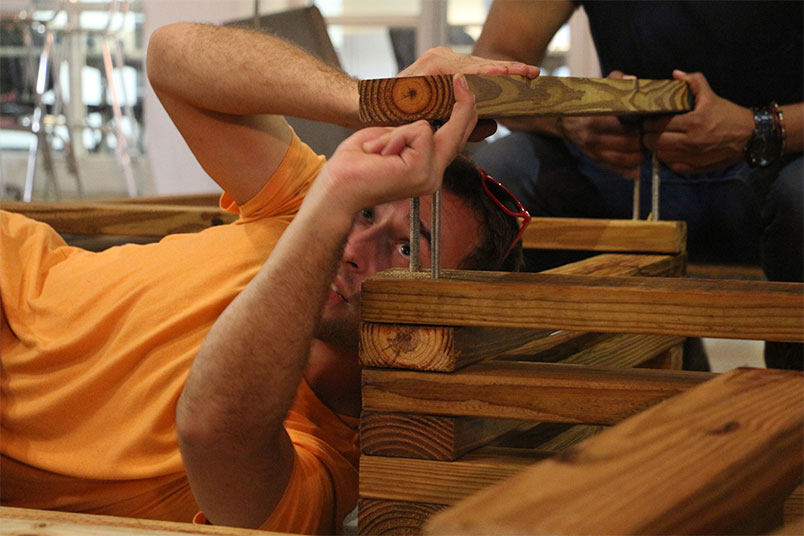 NYIT architecture students layer wooden beams.