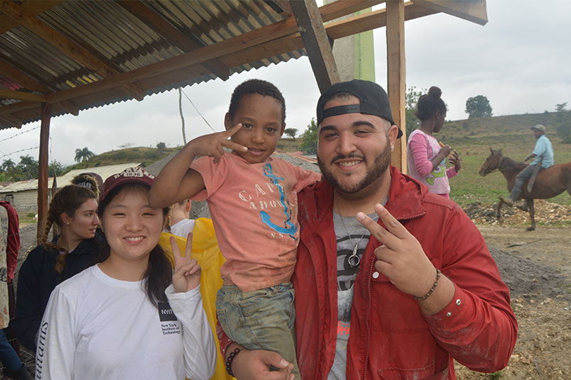 Students Yan Xu and Bryan Diaz strike a pose with a local child.