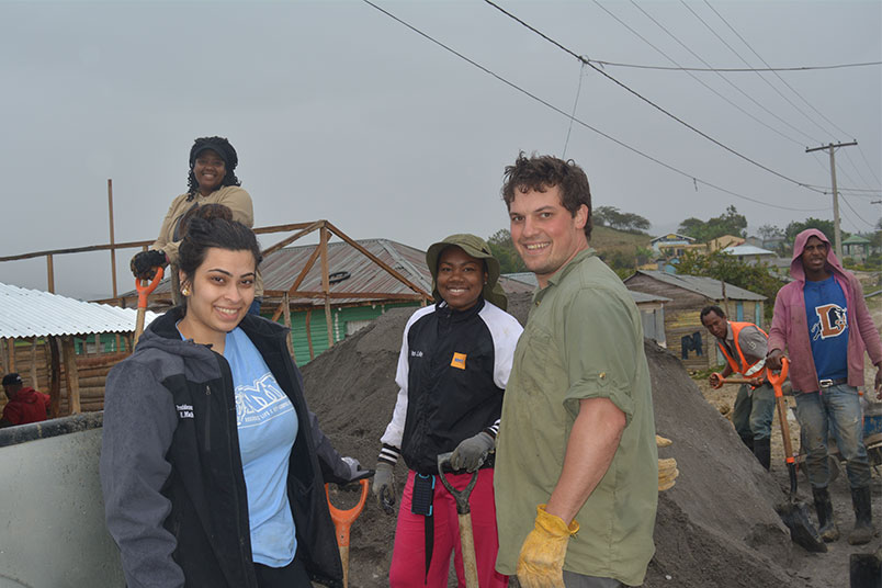 Miranda VanOmmeran (rear), and NYIT students Melissa Mahadeo and Chanelle Sears, with community youth center volunteer, Dan, preparing to shovel gravel into wheelbarrows.