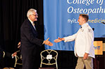 NYIT President Hank Foley shakes hands with a newly coated medical student.